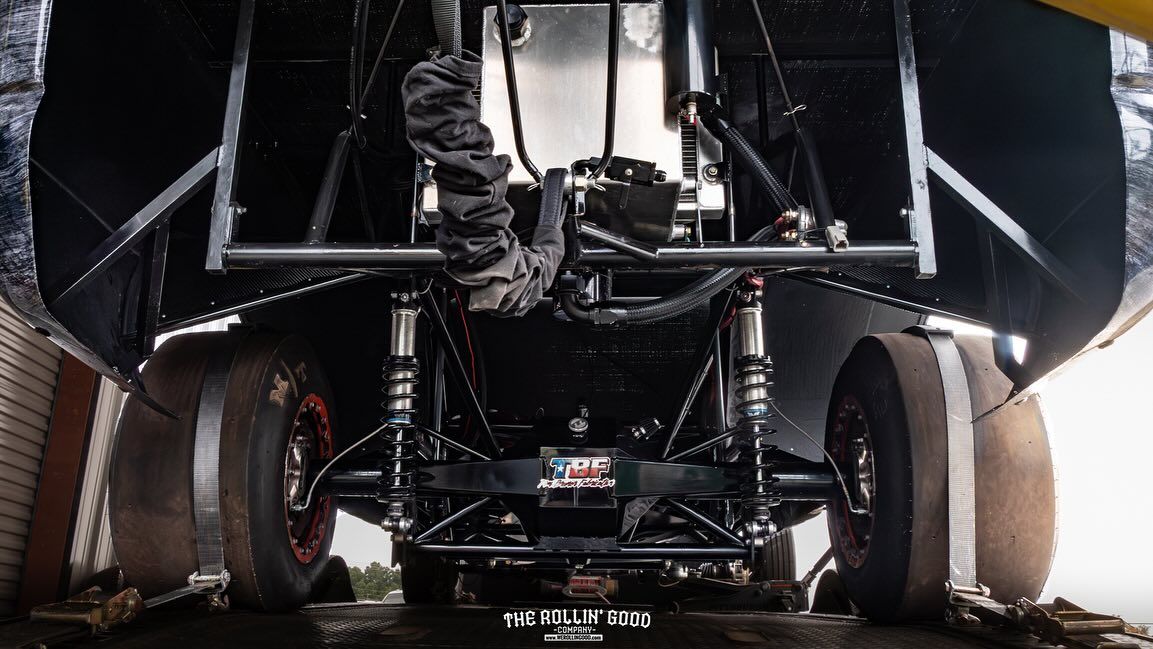 Undercarriage view of a large off-road vehicle with oversized tires and suspension on rough ground