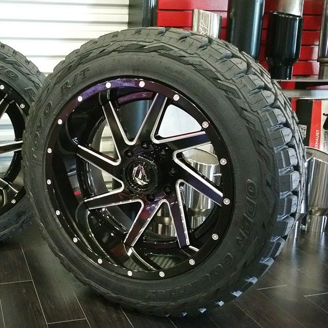 Large off-road tire on a black and purple custom wheel in a showroom