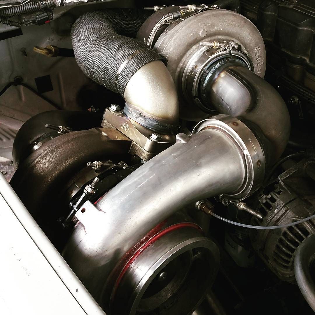 Close-up of a car engine with turbo piping and heat-wrapped hoses inside the engine bay