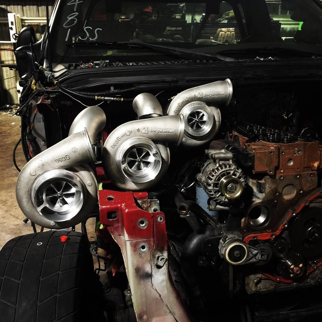 Car engine with four silver turbochargers mounted on the front in a garage setting