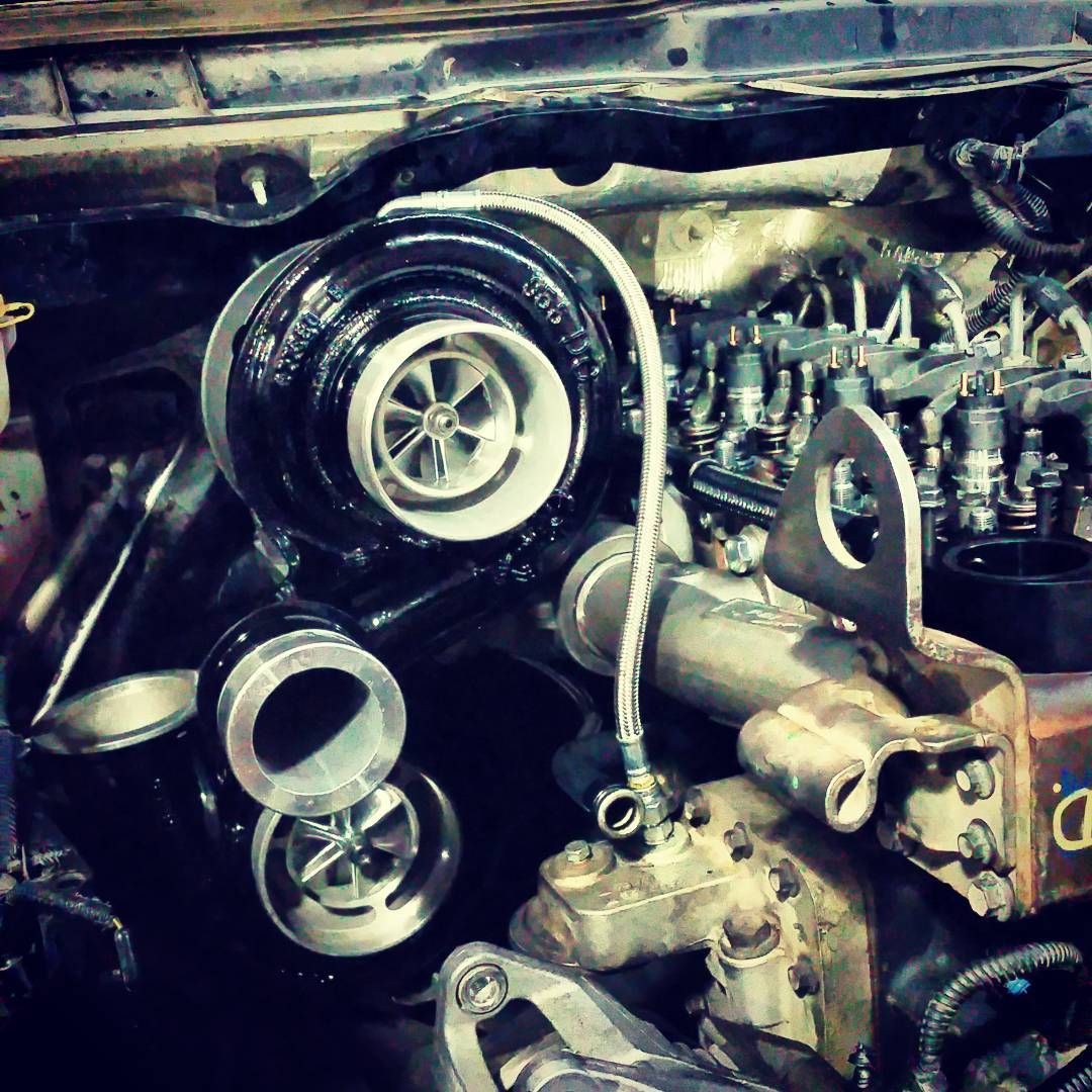 Close-up of a car engine with exposed turbocharger and metallic mechanical components.