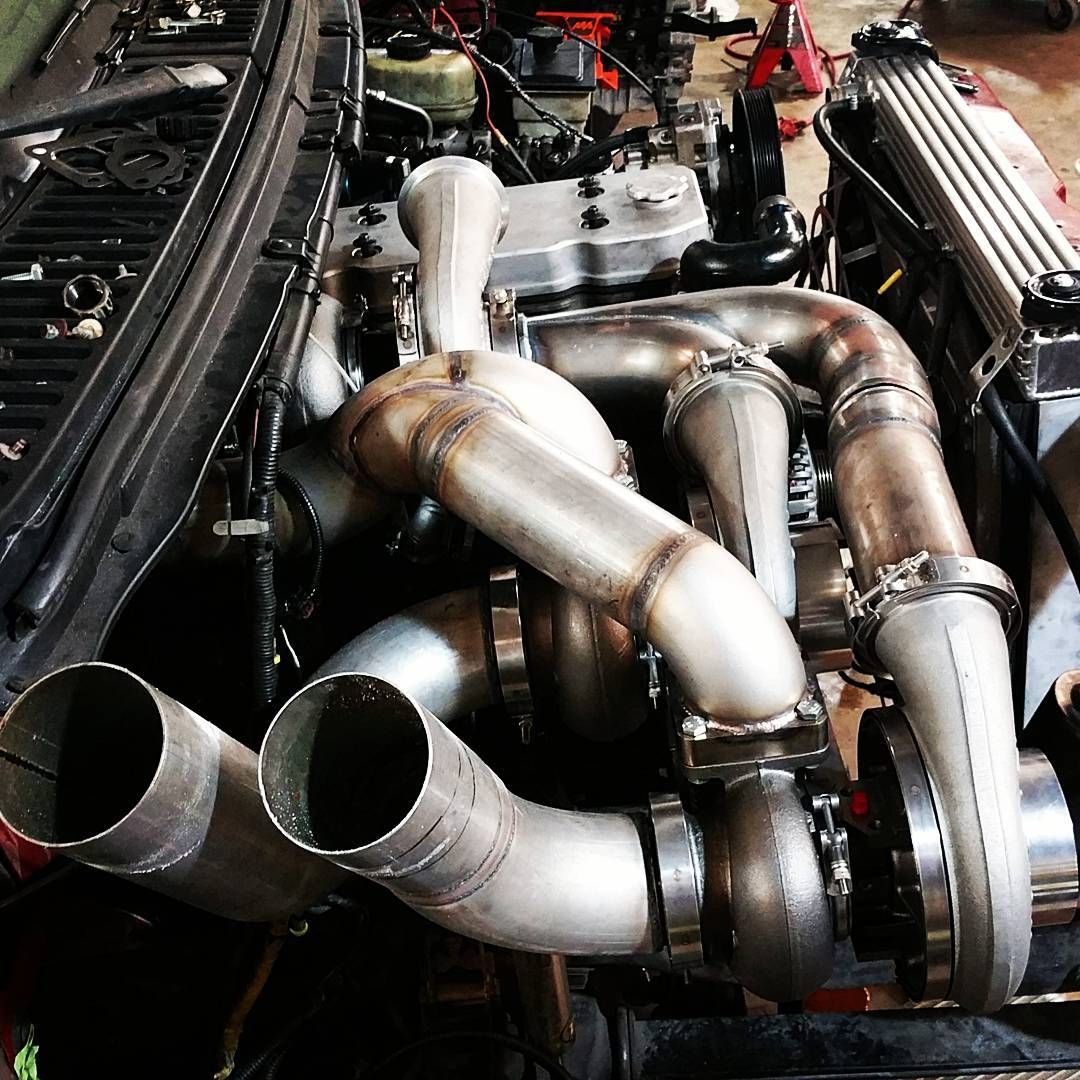 Close-up of a car engine bay with polished turbo piping and twin exhaust outlets