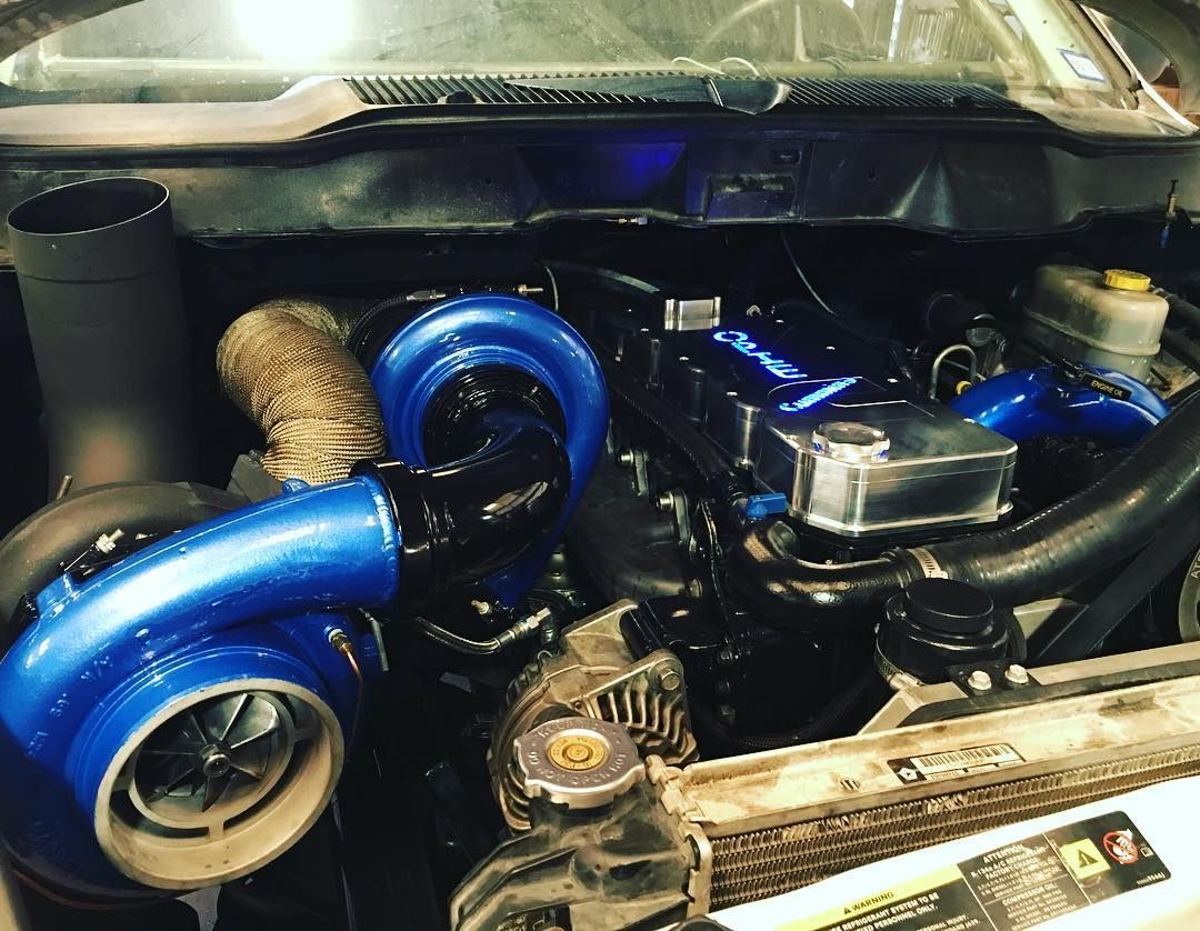 Close-up of a car engine with bright blue turbo piping and metallic components under the hood