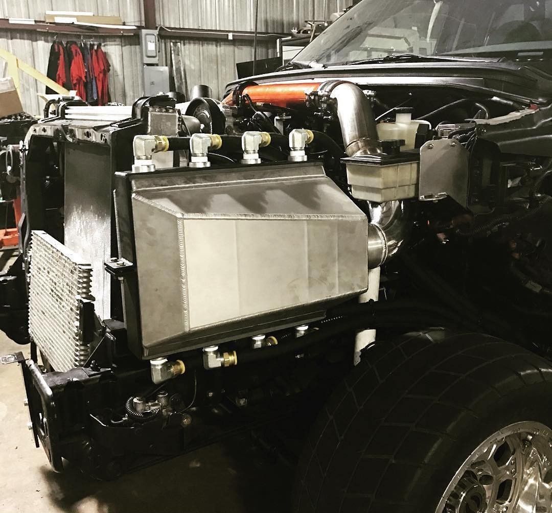 Modified car with exposed engine and large silver intercooler in a workshop