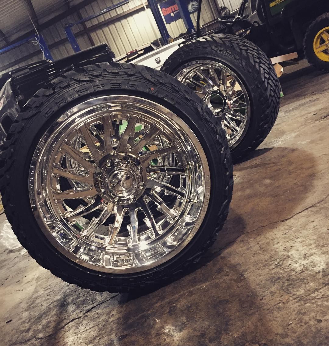 Chrome truck wheels with large off-road tires in a workshop garage