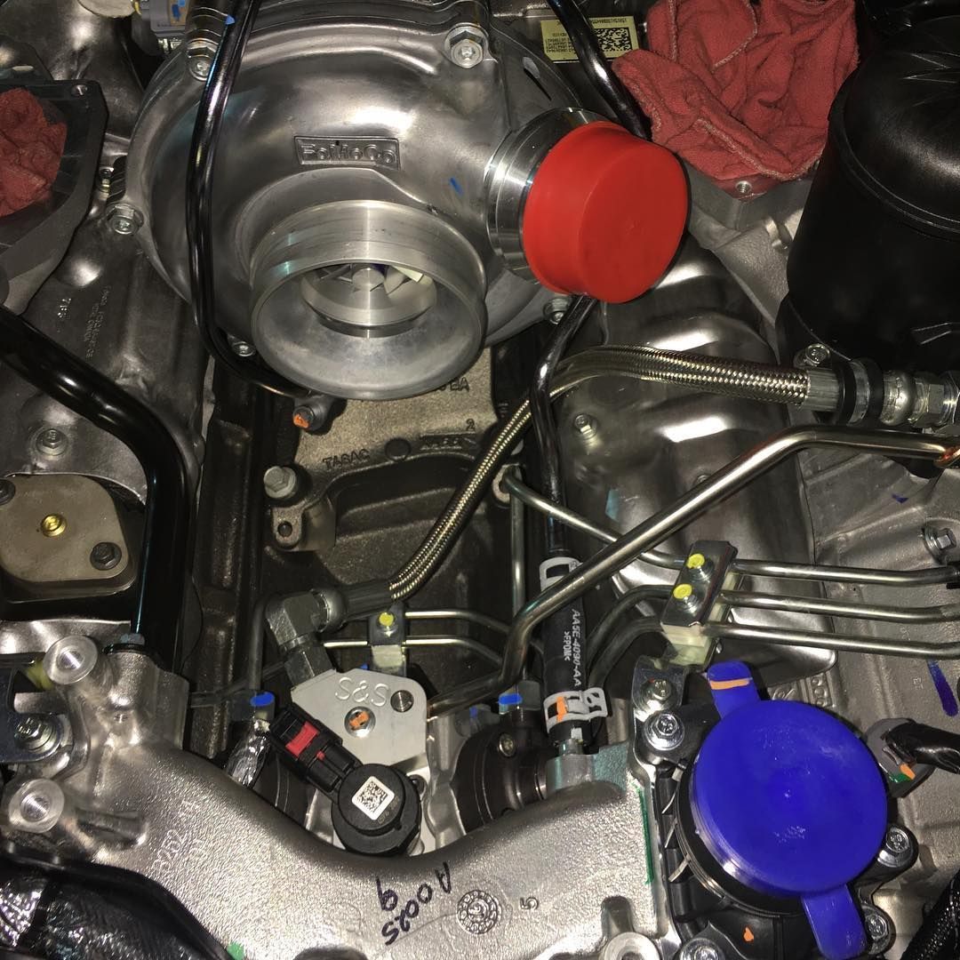Close-up of a car engine bay with a silver turbocharger and red and blue caps
