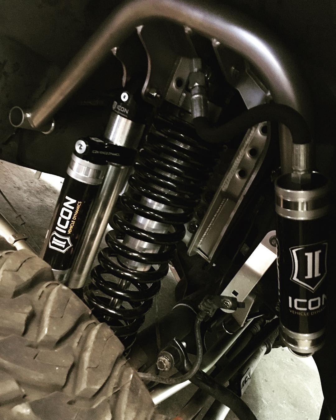 Close-up of a motorcycle suspension with black Icon shocks and springs inside a wheel well