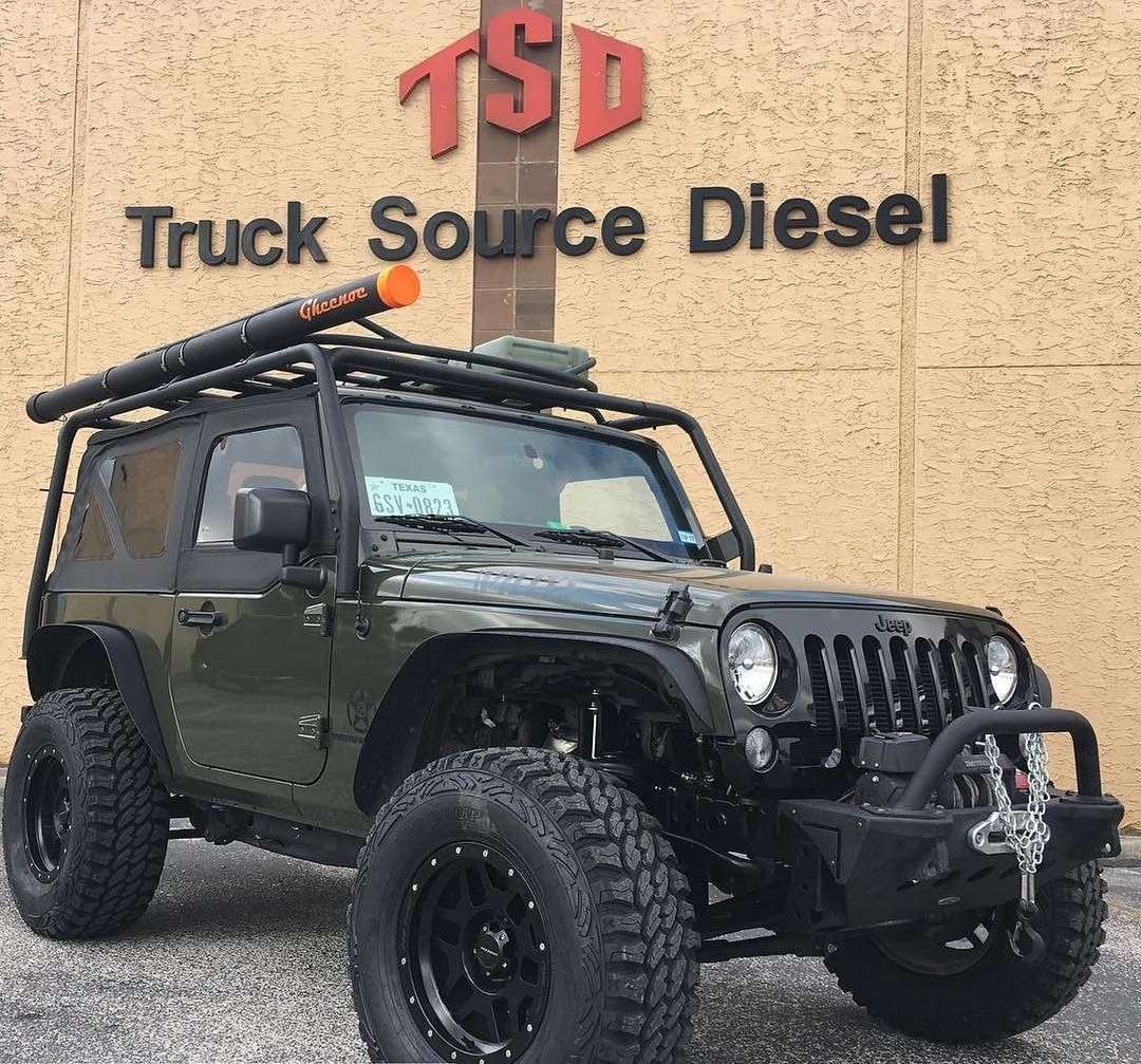 Green off-road Jeep with roof rack parked in front of Truck Source Diesel sign