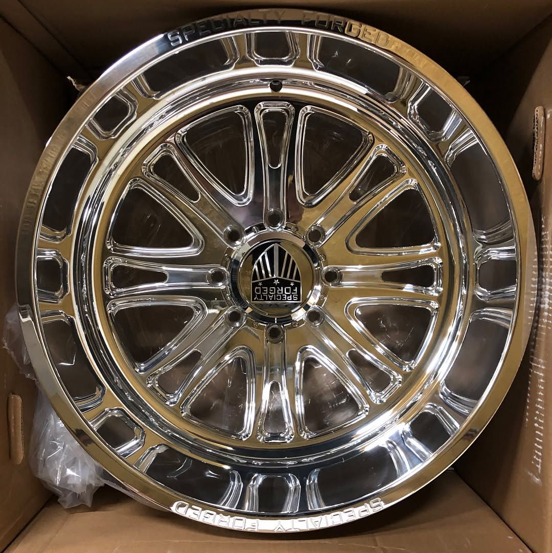 Chrome car wheel rim in a cardboard box, with a shiny multi-spoke design.