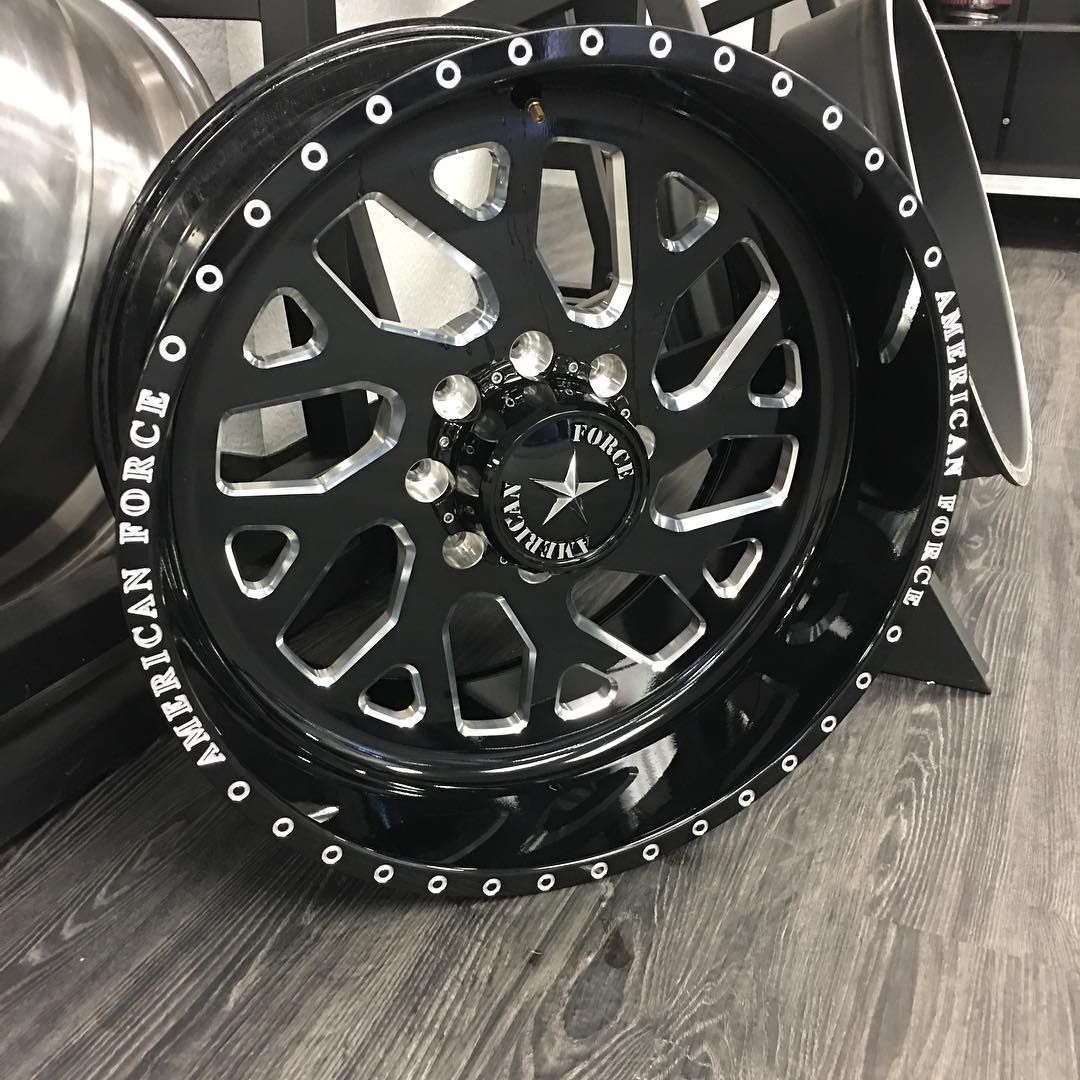 Black off-road wheel rim with silver bolt accents and white lettering, displayed indoors on a carpet.