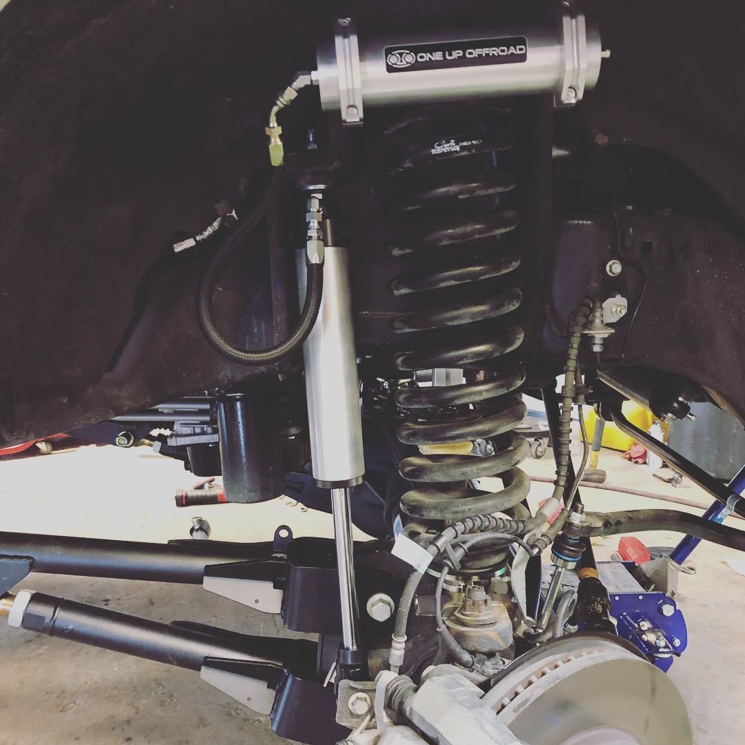 Close-up of a vehicle suspension with coil spring, shock absorber, and steering components under the wheel well