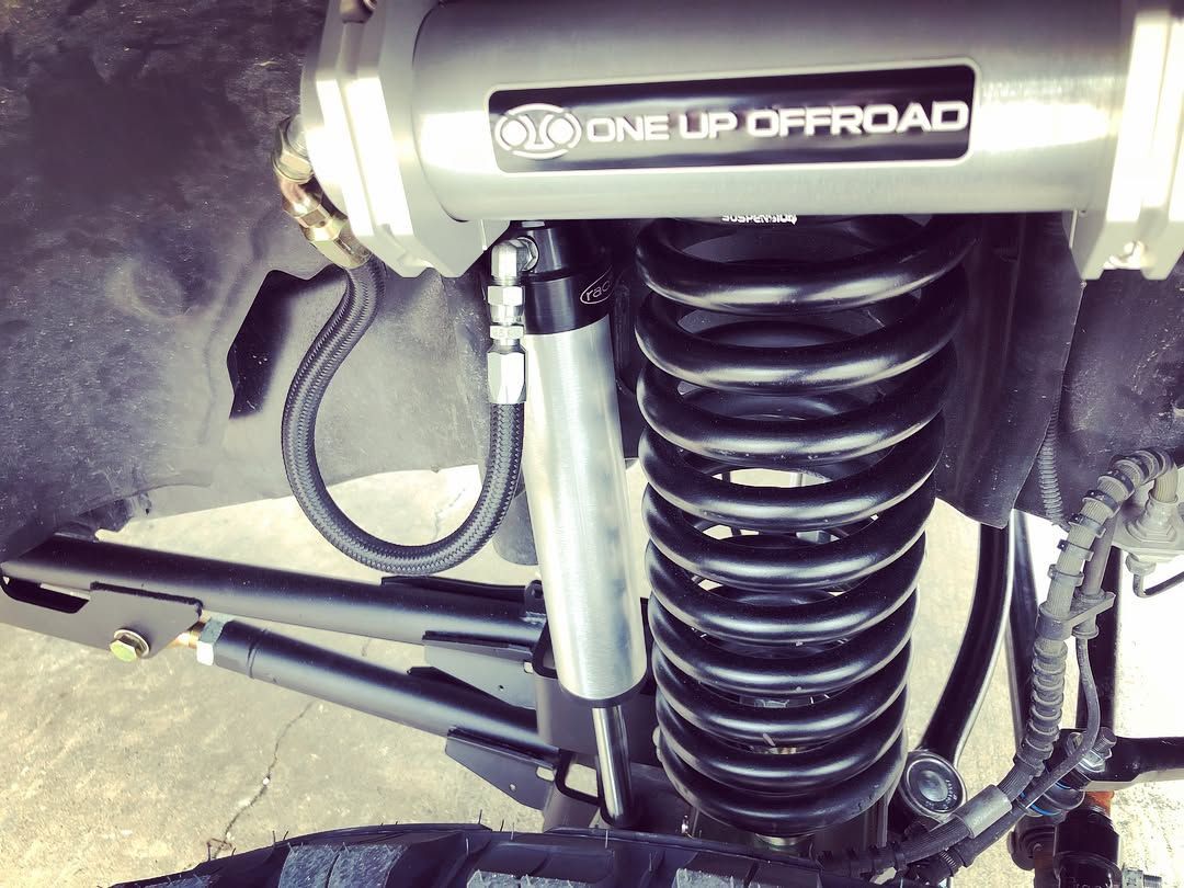 Close-up of a vehicle off-road suspension with coil spring and shock absorber.