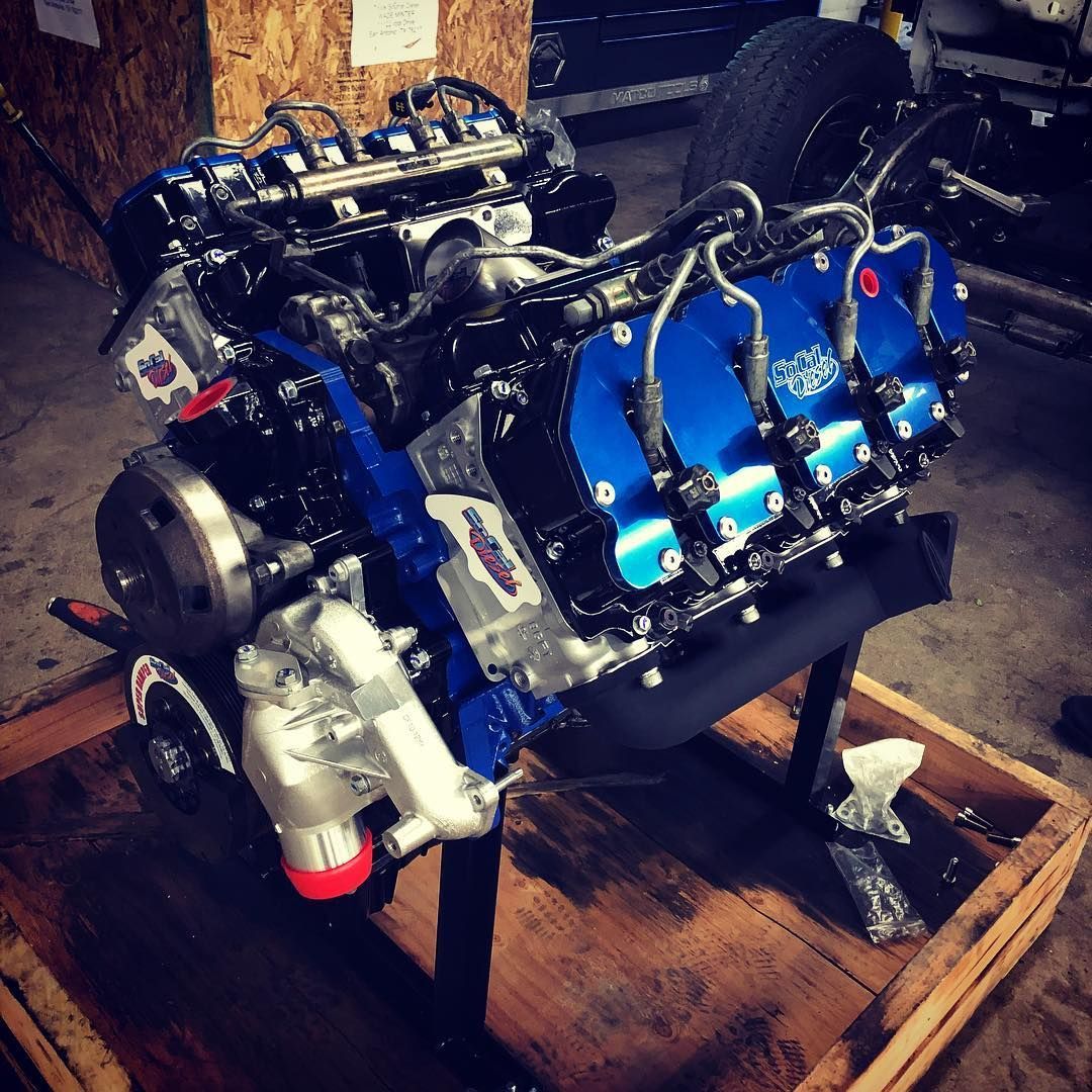 Blue and black engine mounted on a wooden crate in a workshop
