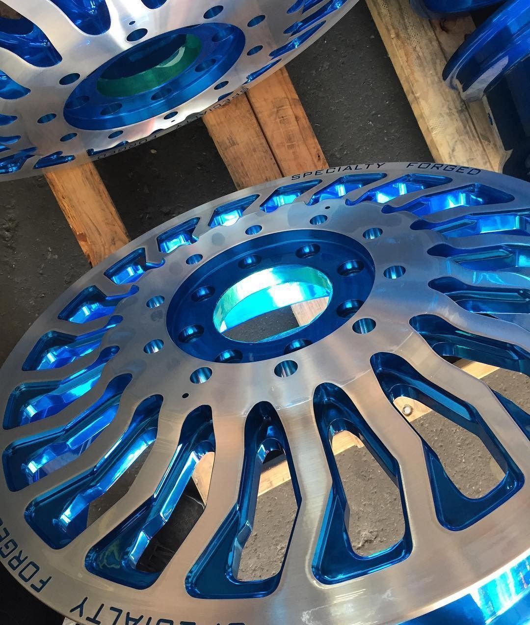 Blue anodized metal wheel or gear parts stacked in a workshop setting