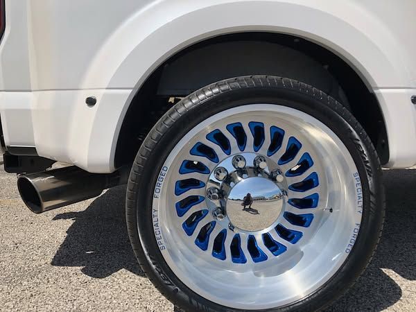 White vehicle with a shiny chrome wheel and black tire, parked on pavement