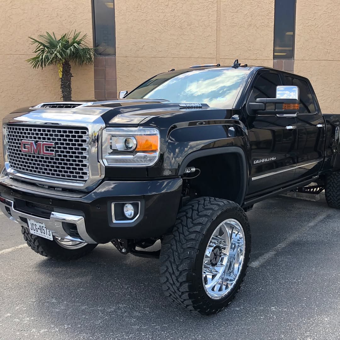Black GMC pickup truck with lifted suspension parked in front of a building