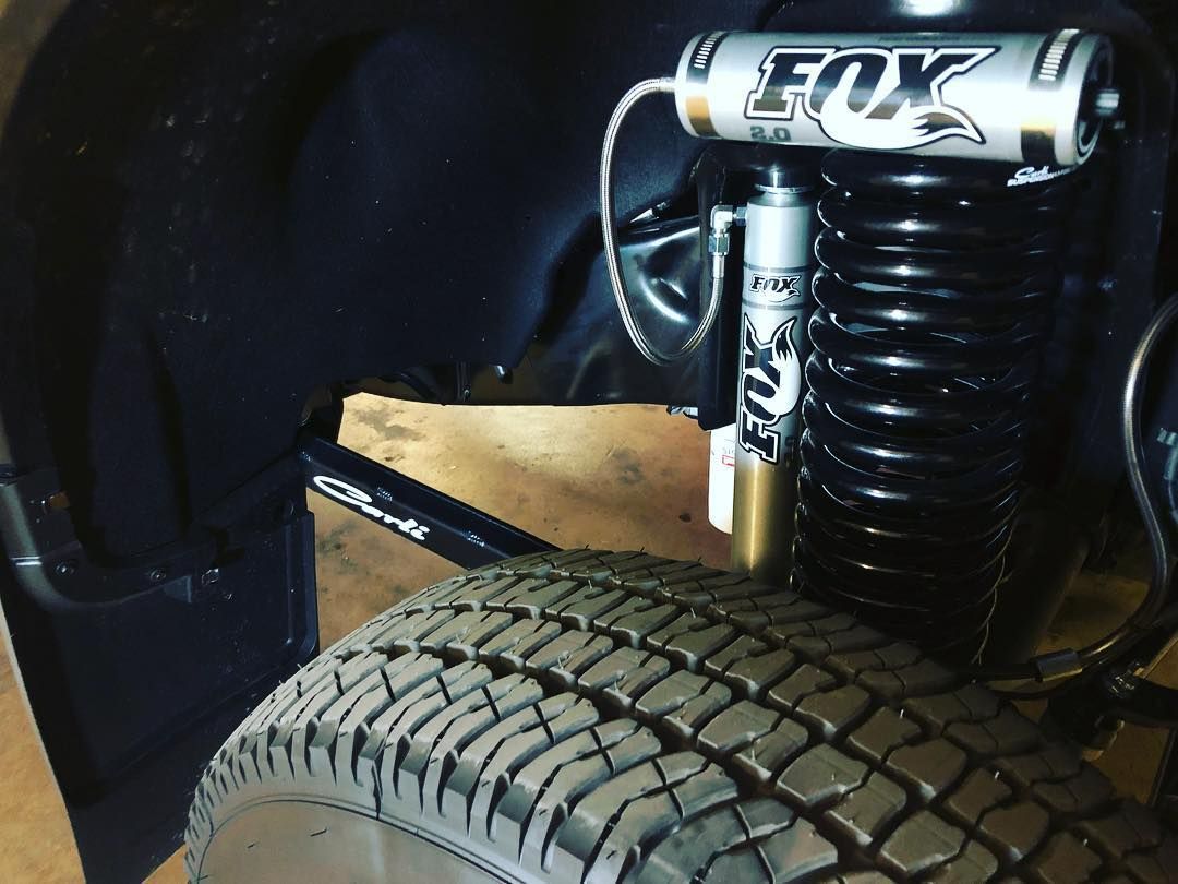 Close-up of a vehicle suspension with a FOX shock absorber and large off-road tire.