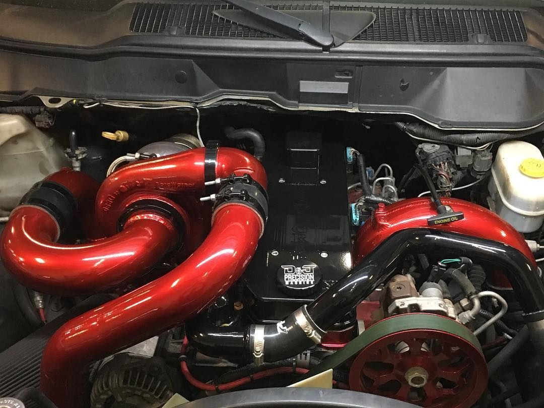 Engine bay with bright red performance intake piping and visible accessories under the hood