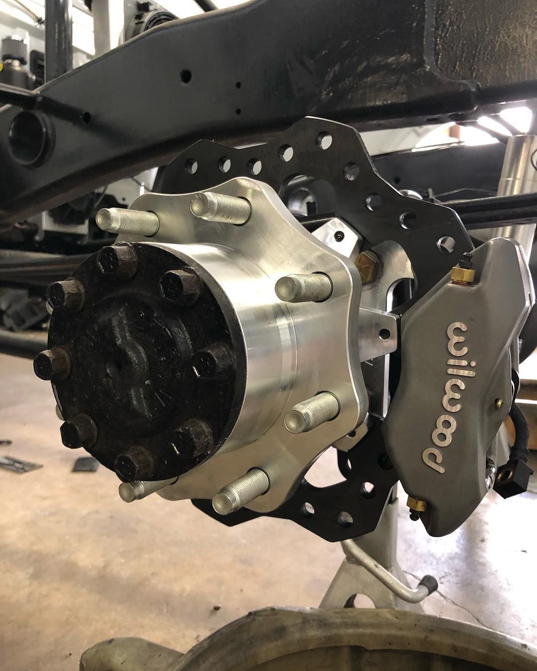 Close-up of a car brake assembly with a black Wilwood caliper on a wheel hub.