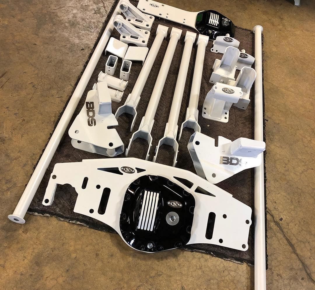 Scattered white and black metal parts, pipes, and hardware laid out on carpet for assembly