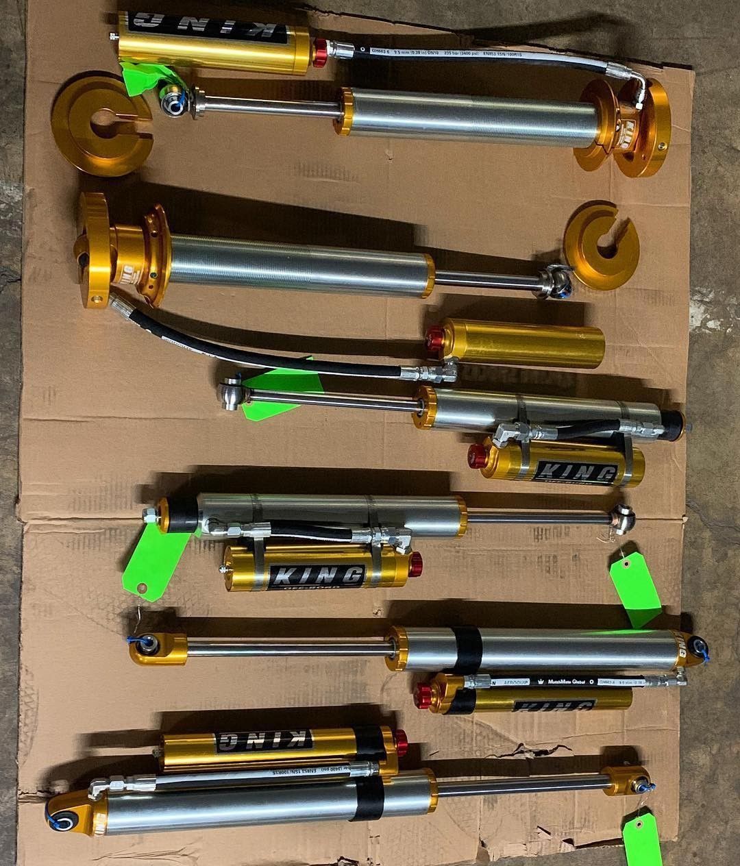 Assorted metal cylinder components with gold fittings and black tubes arranged on cardboard.
