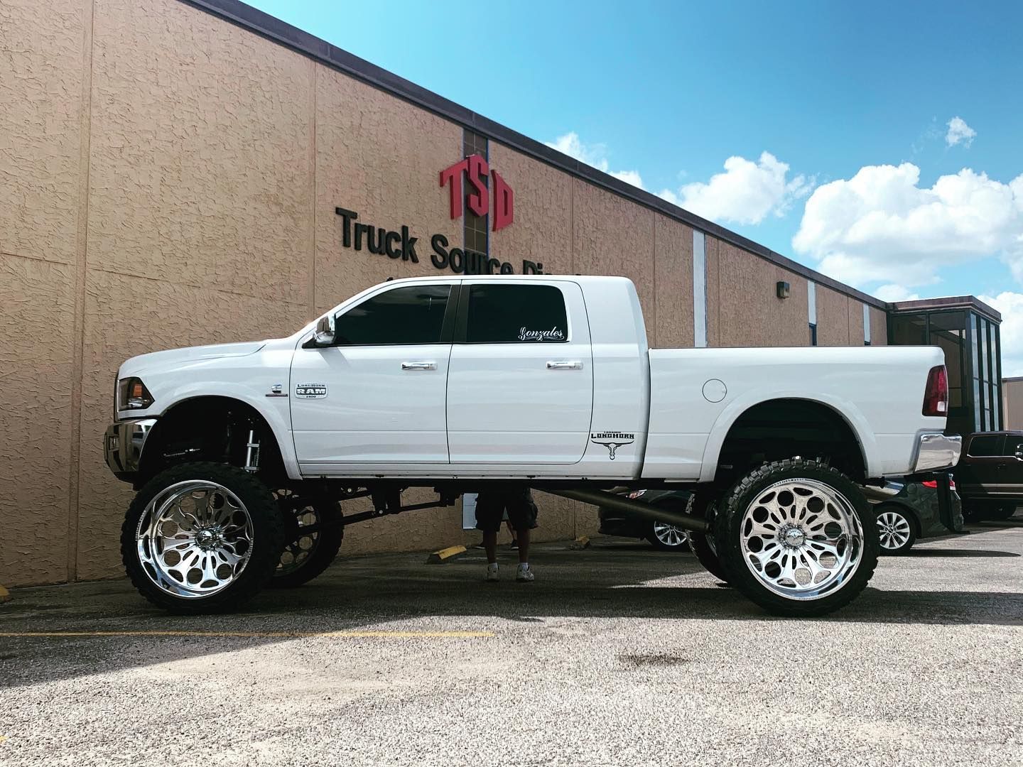 White lifted pickup truck parked outside a truck shop building.