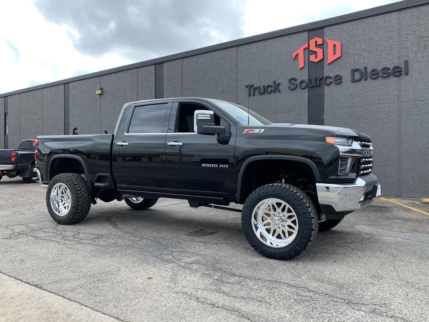 Black lifted pickup truck parked outside a Think Source Diesel building