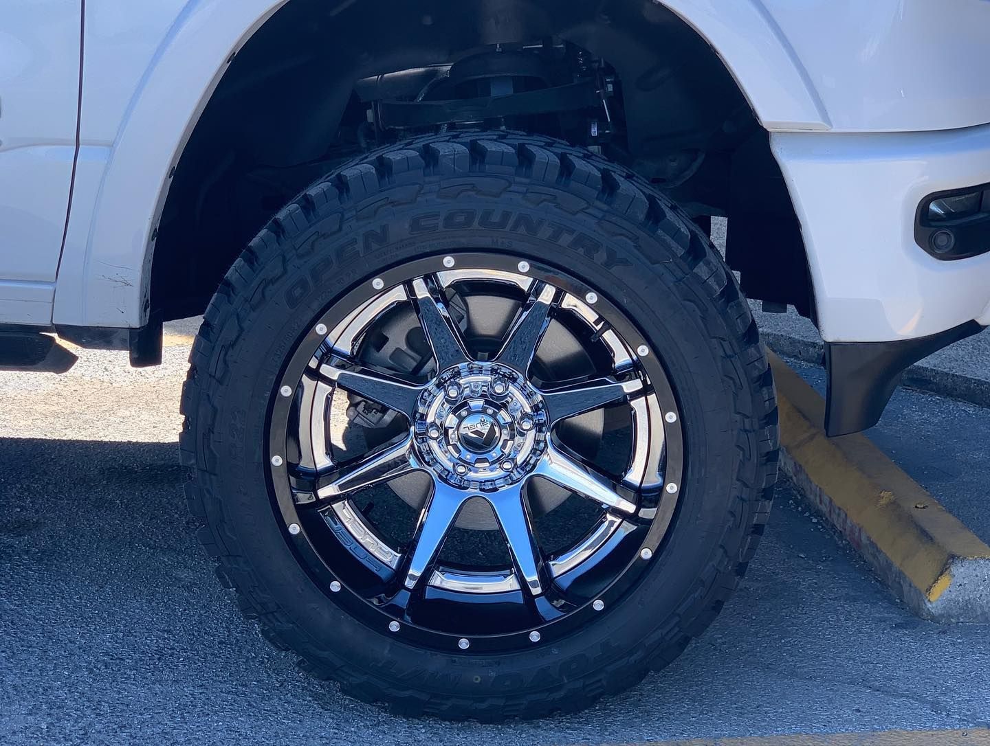 Close-up of a truck’s black and chrome off-road wheel and tire on pavement