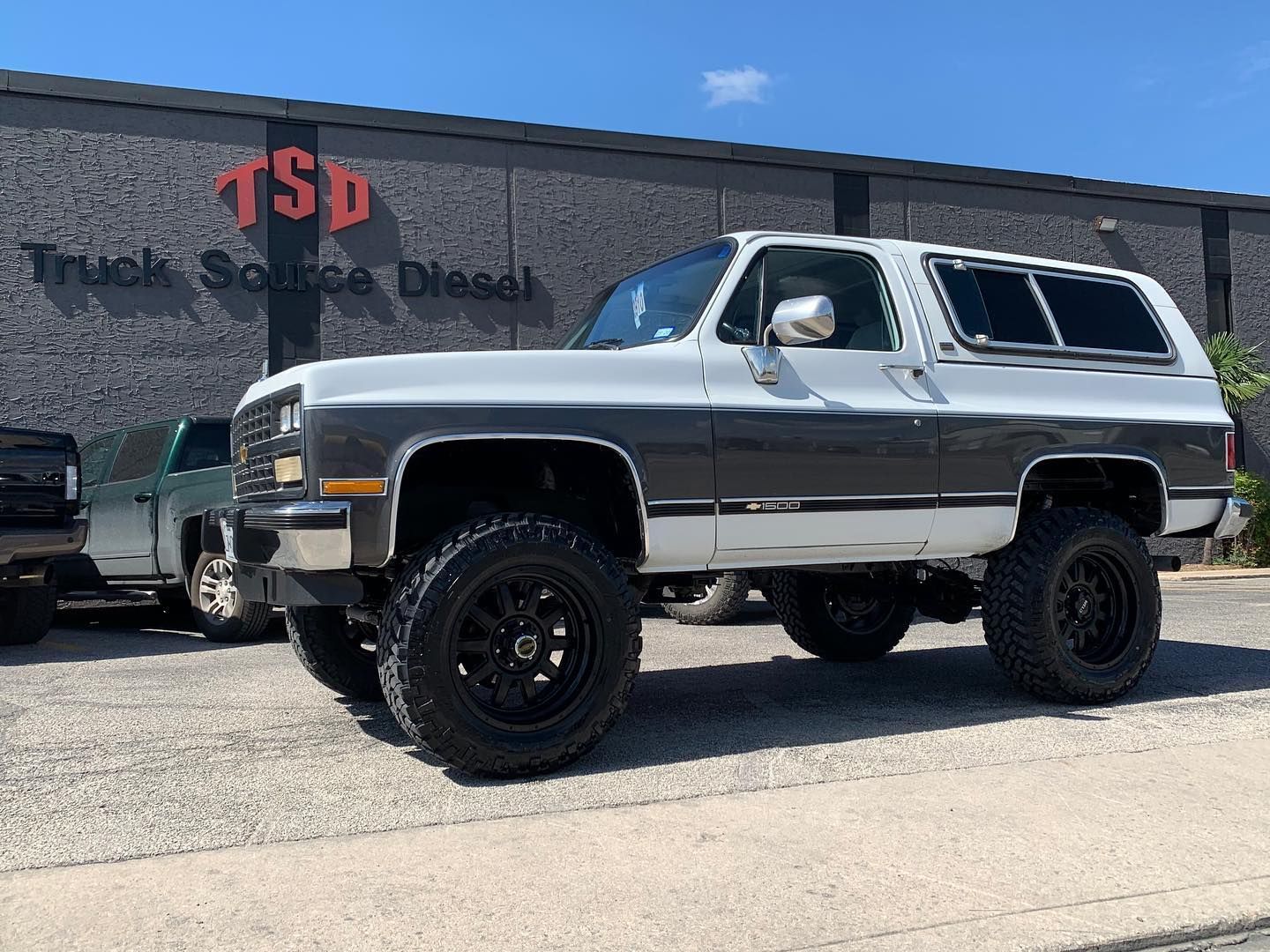 Lifted silver and black SUV parked outside a truck sales diesel shop