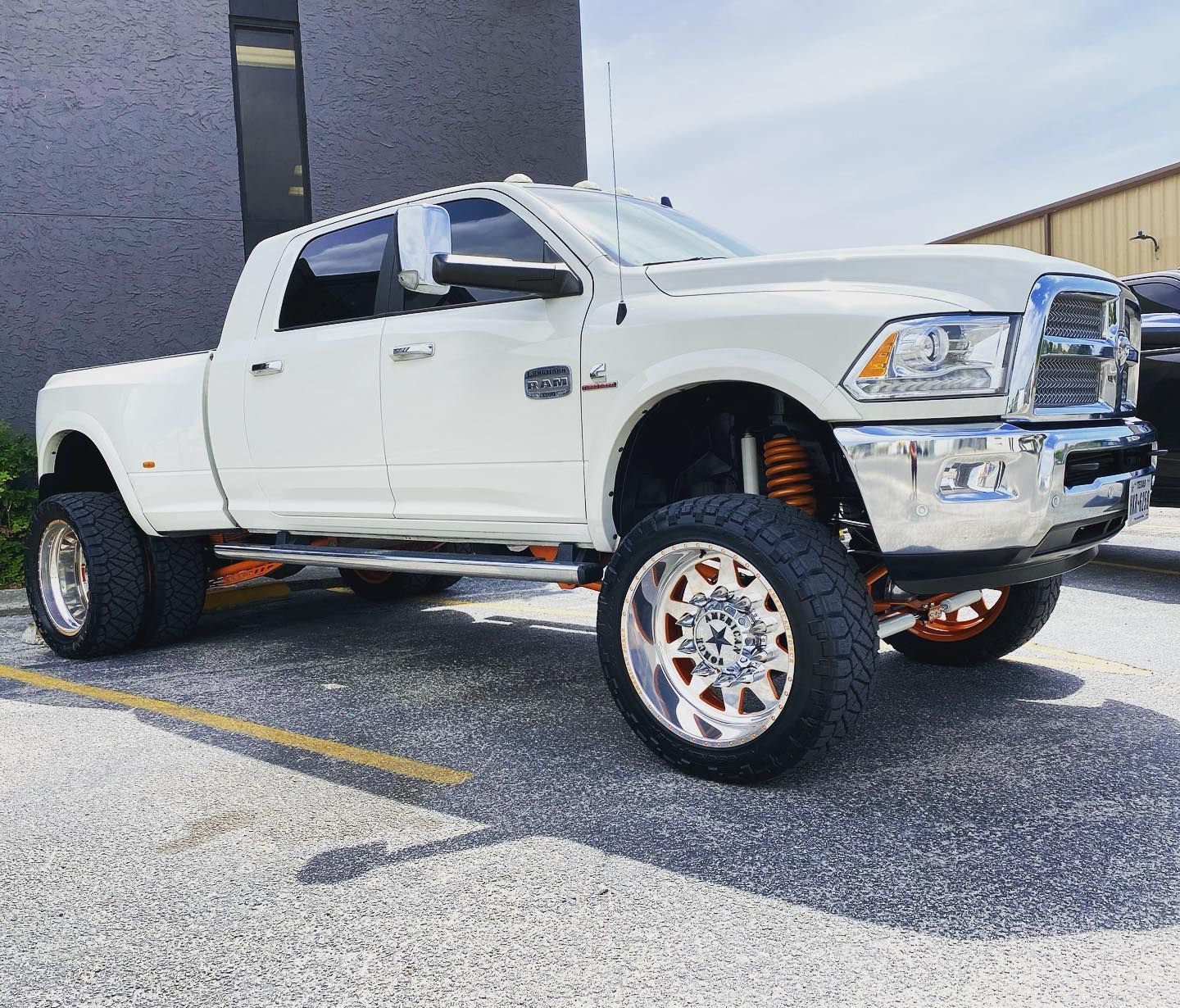 White lifted pickup truck parked on pavement beside a building
