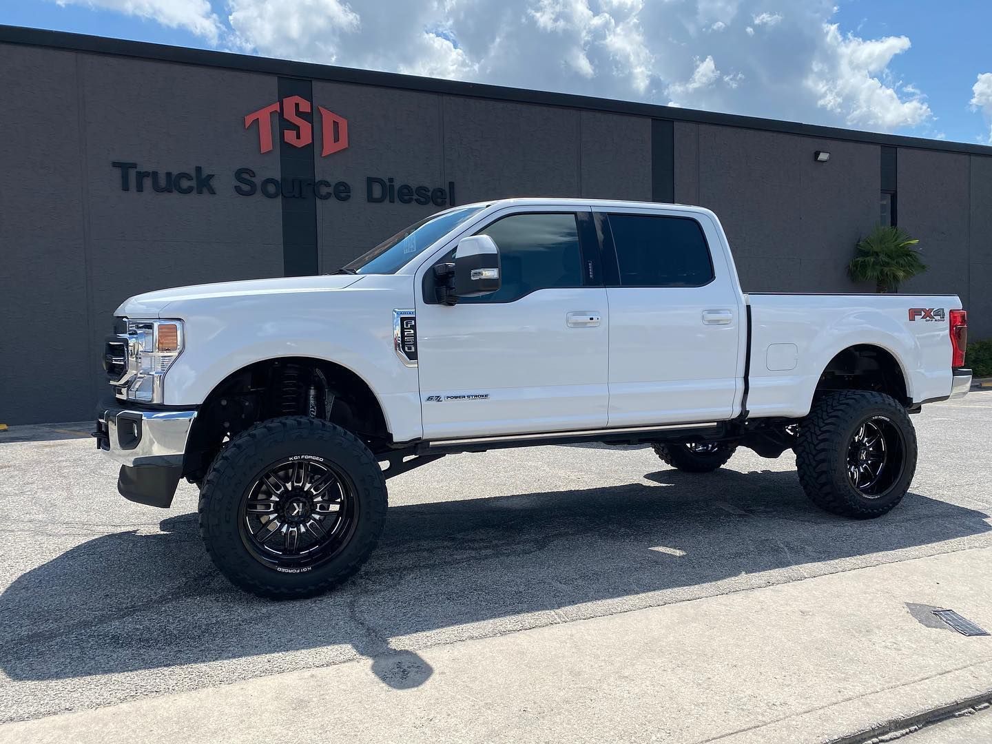 White lifted pickup truck parked outside Truck Source Diesel building