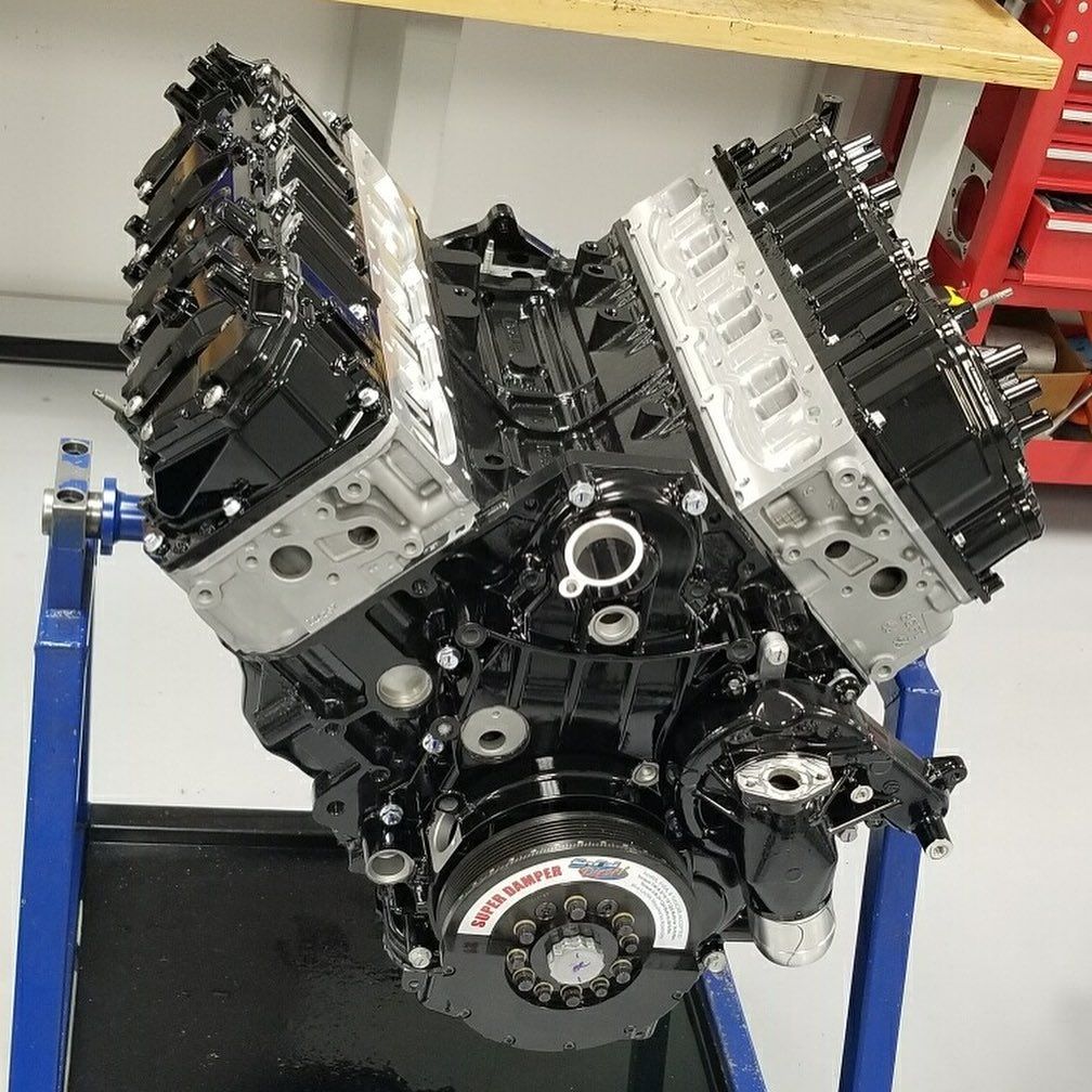 V-shaped car engine on a blue stand in a workshop, with black and silver components exposed
