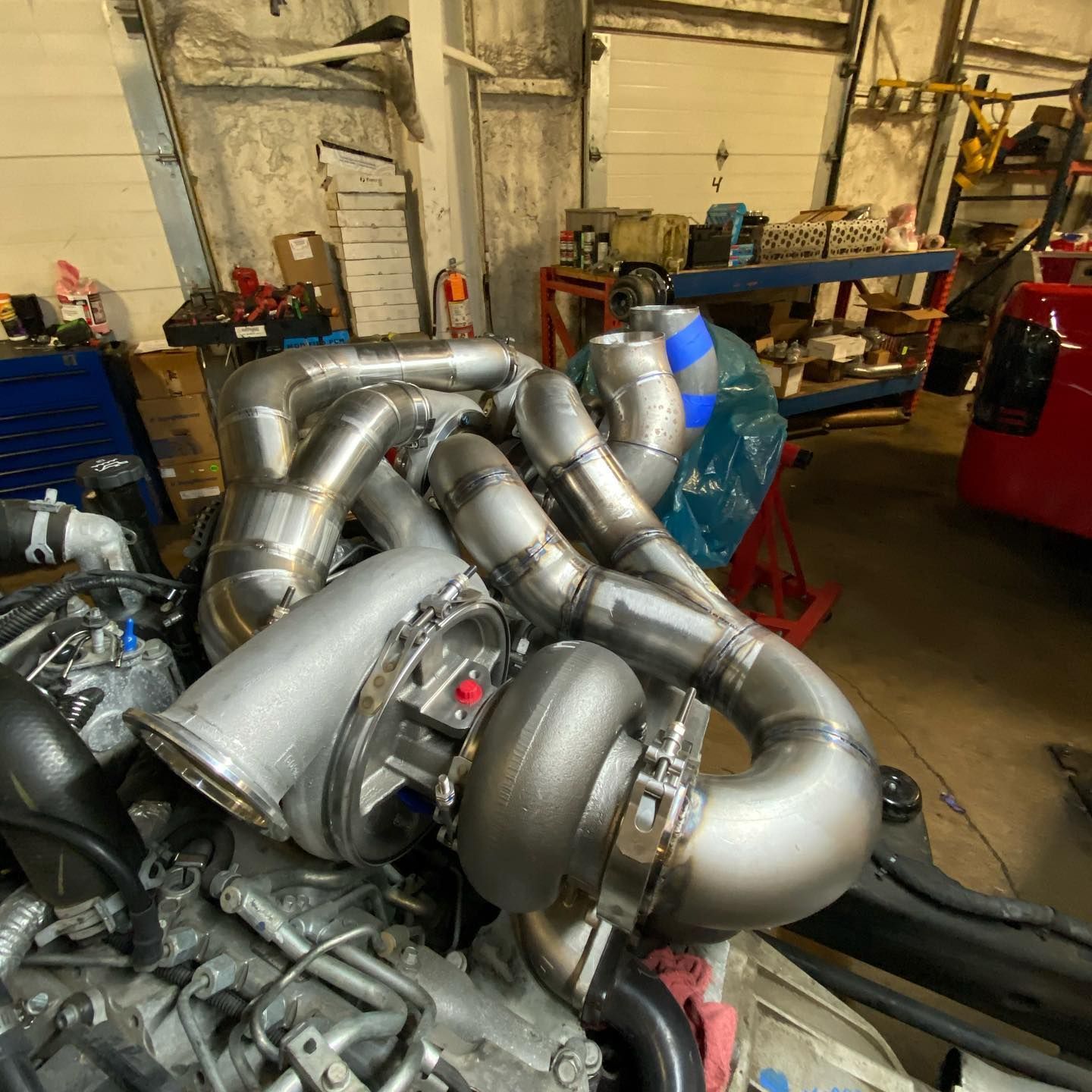 Turbo engine with silver pipes and fittings in a workshop, surrounded by tools and equipment
