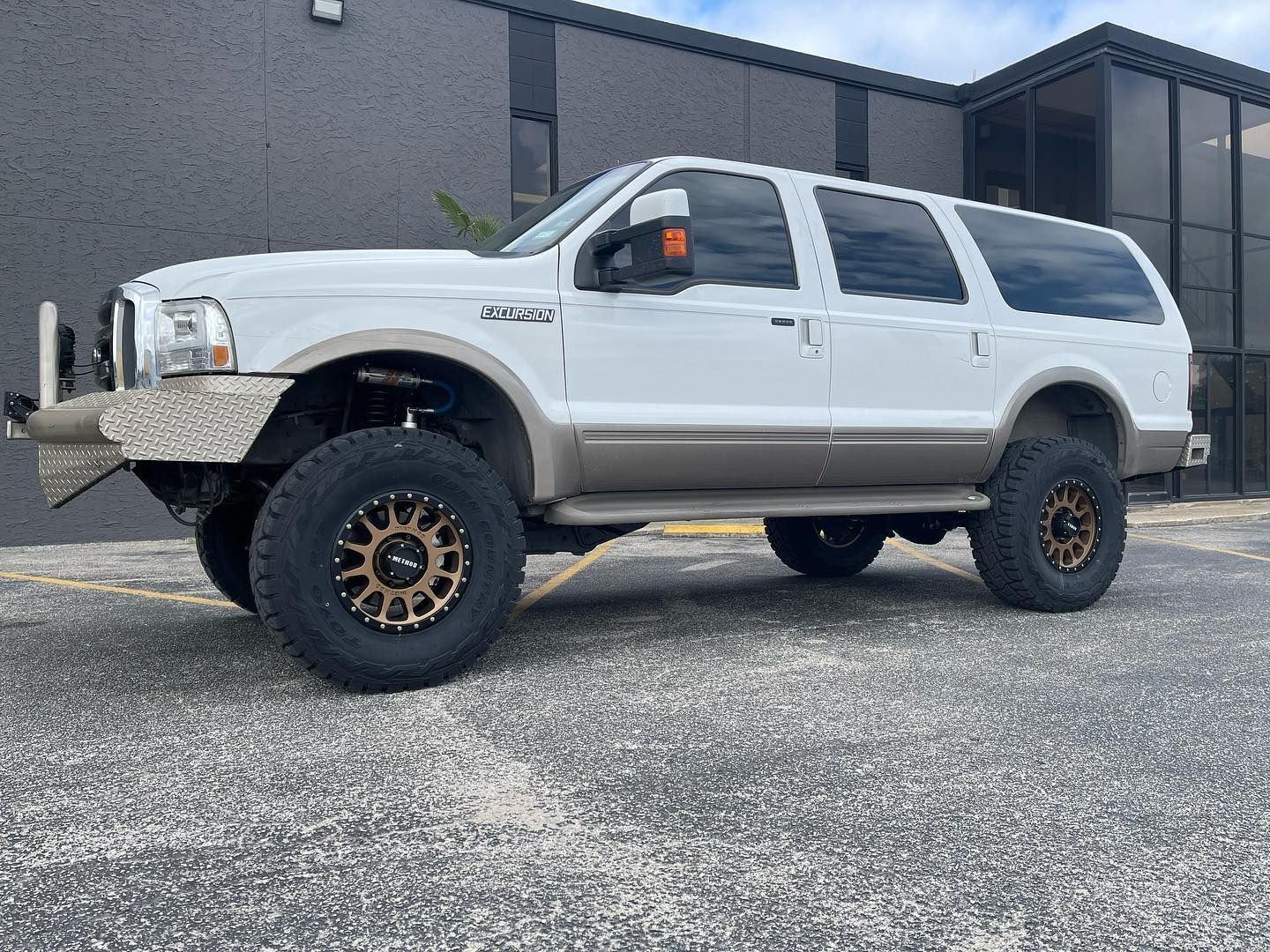 White lifted SUV with off-road tires parked outside a building