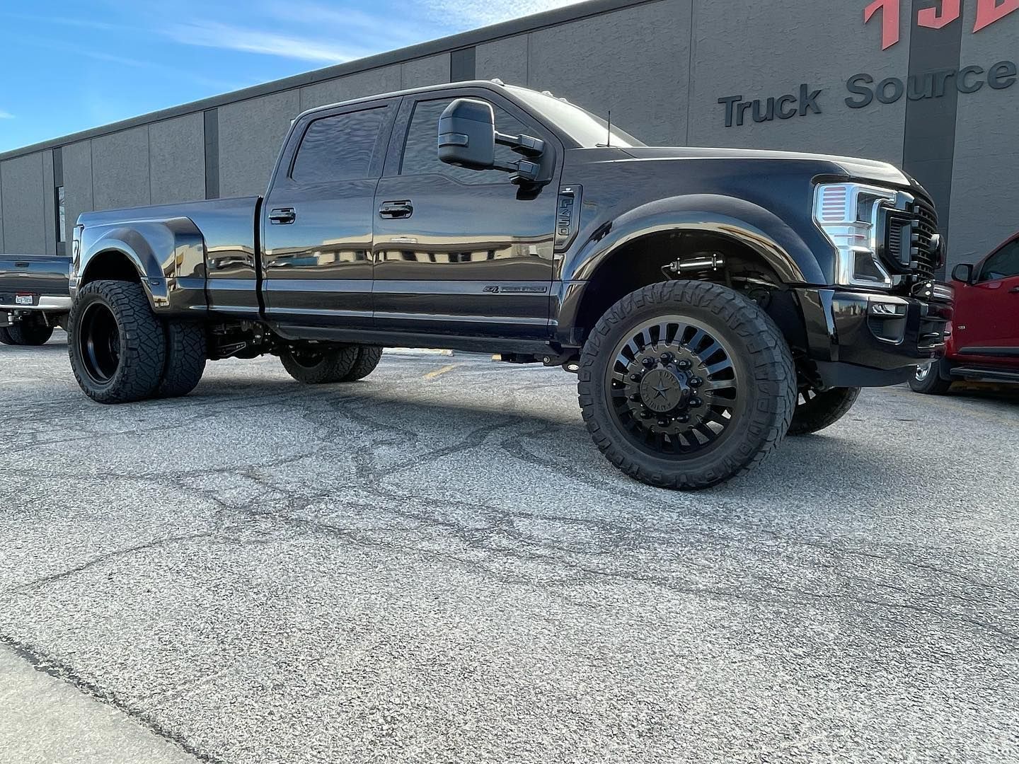 Black lifted pickup truck parked outside a truck shop.