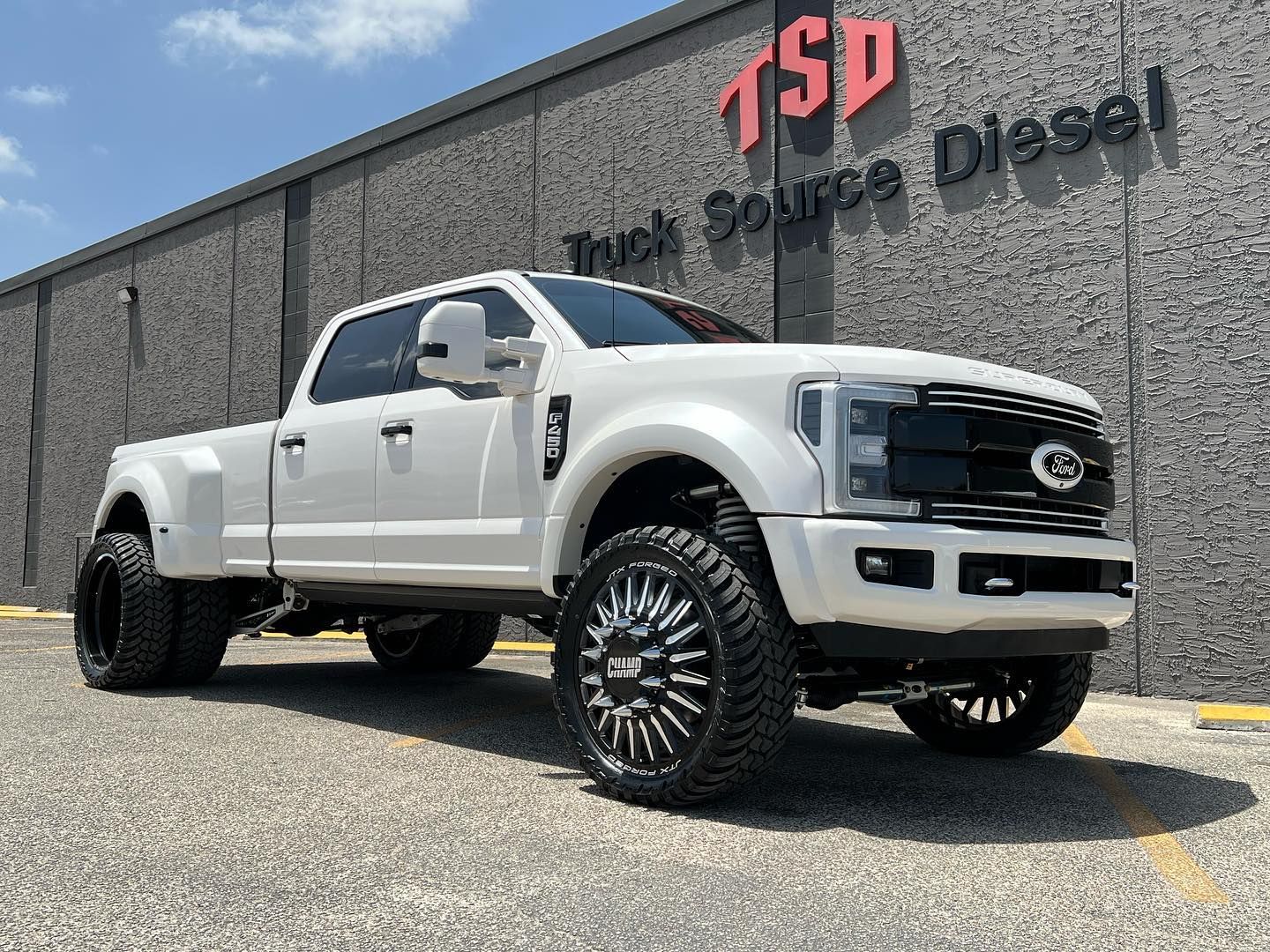 White lifted pickup truck parked outside a TSP truck source diesel building