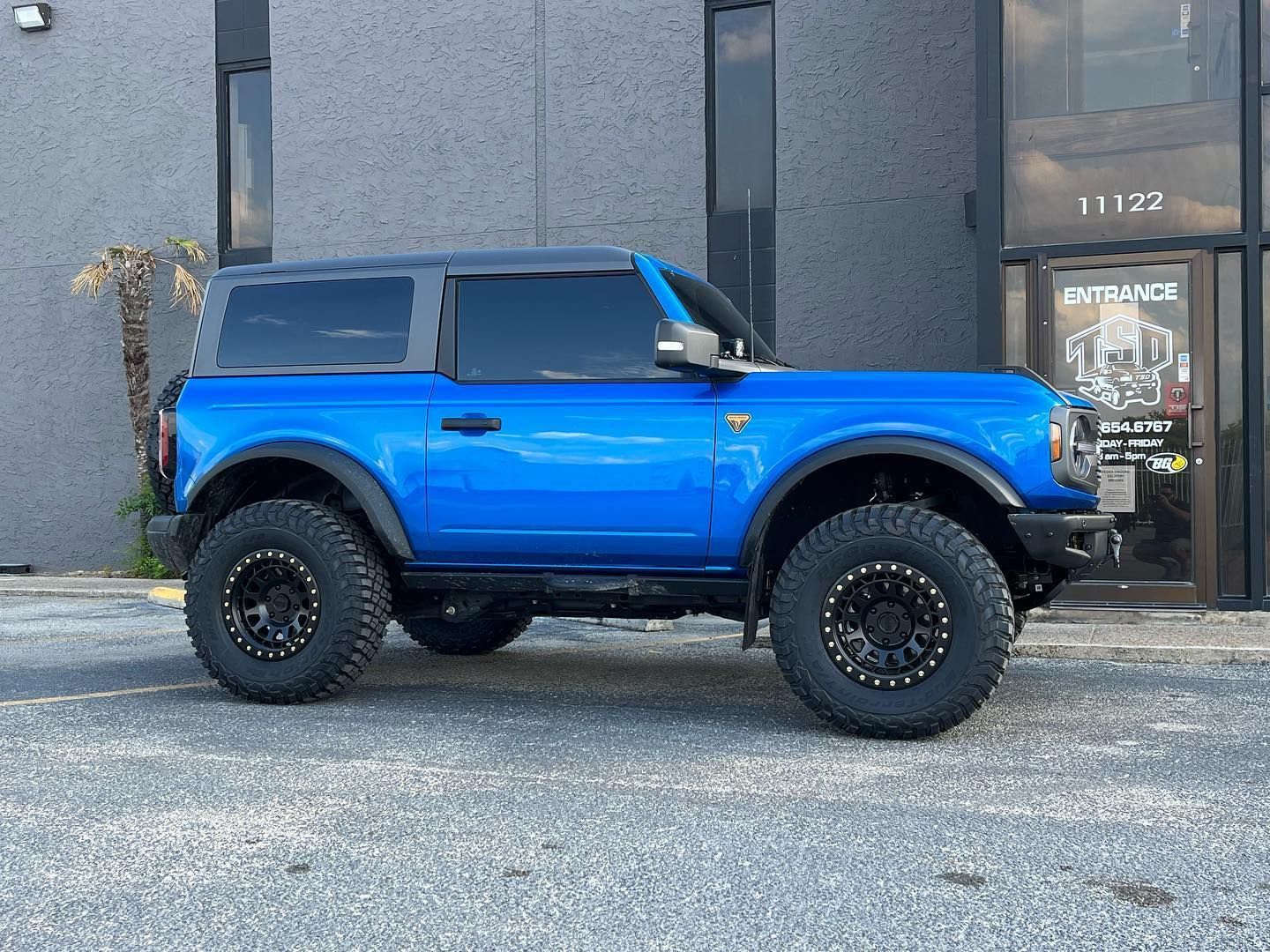 Blue lifted off-road SUV parked outside a building with a gray facade.