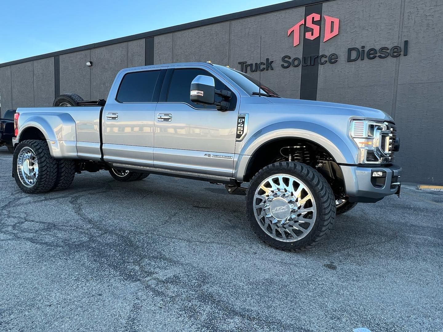 Silver lifted pickup truck parked outside a Truck Source Diesel building
