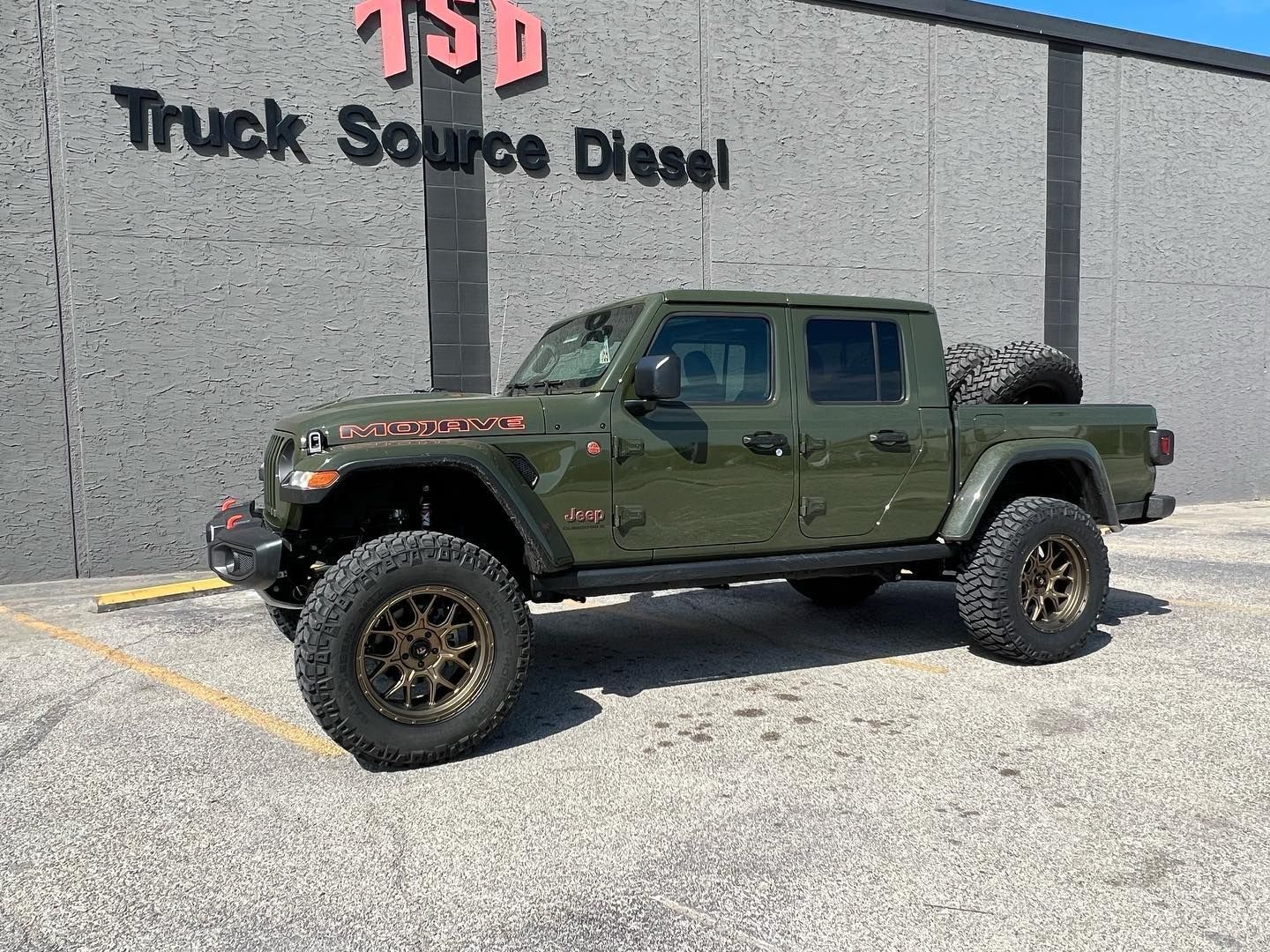 Green Jeep Gladiator truck parked outside Truck Source Diesel building.