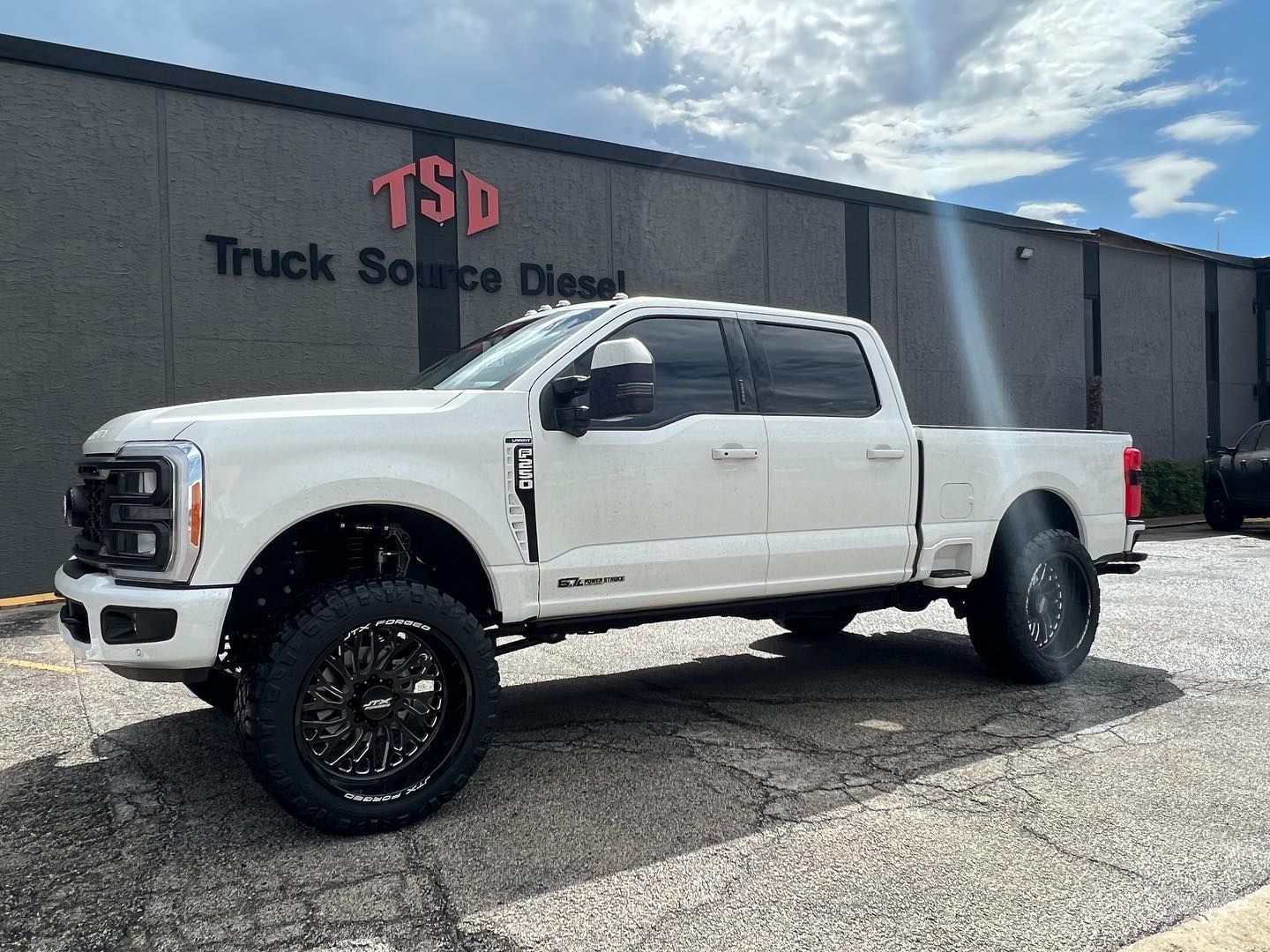 White lifted pickup truck parked outside a truck service dealership.