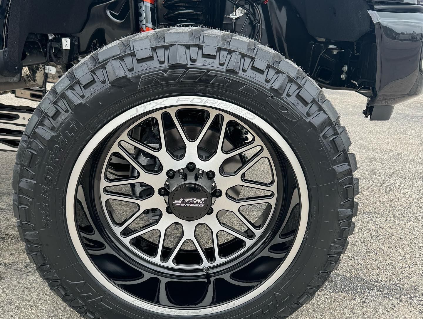 Close-up of a black off-road tire with a silver alloy wheel on a lifted vehicle