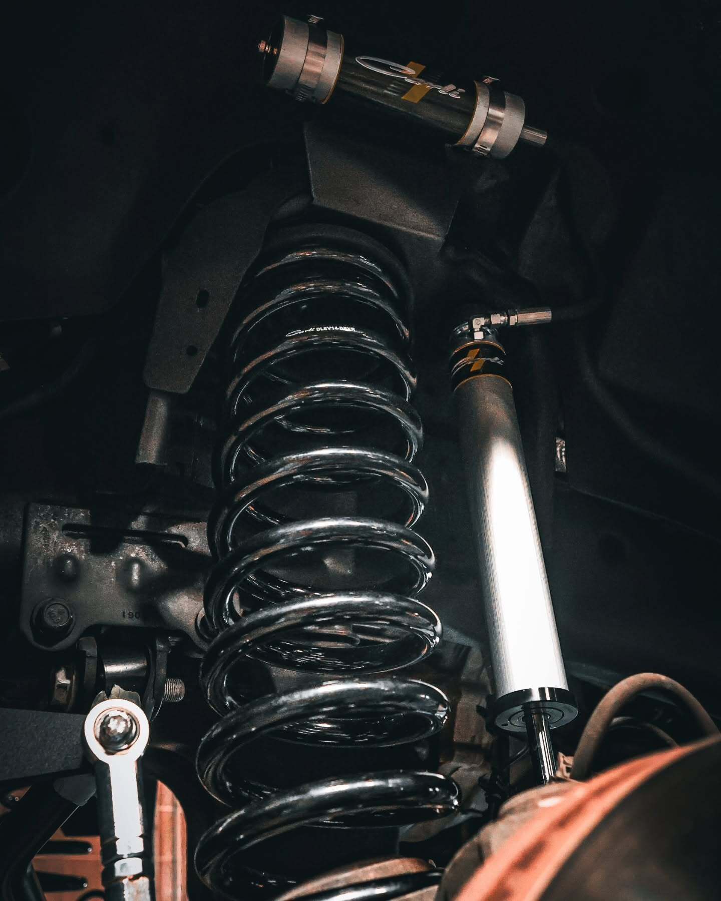 Close-up of a motorcycle suspension spring and shock absorber in a dark frame area