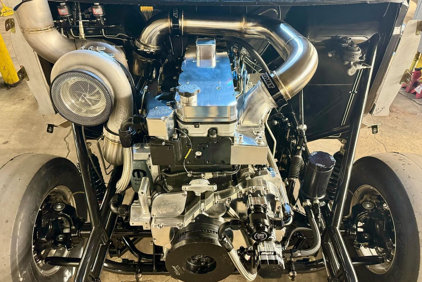 Car engine bay with twin turbochargers and polished piping, viewed from the front