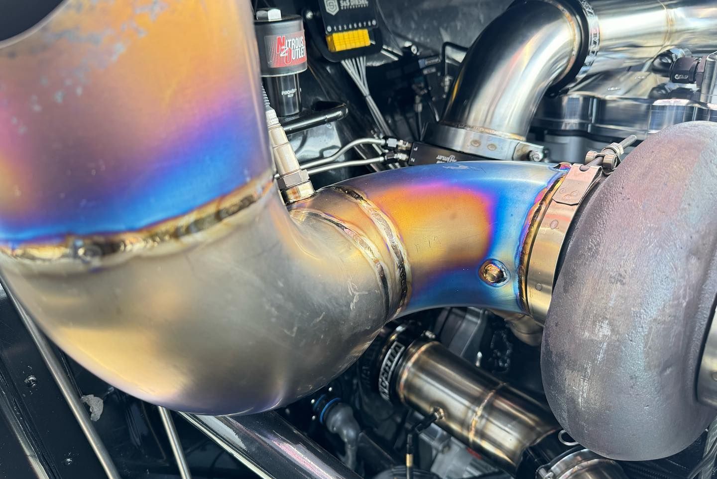 Close-up of welded metal exhaust piping with blue heat discoloration in an engine bay