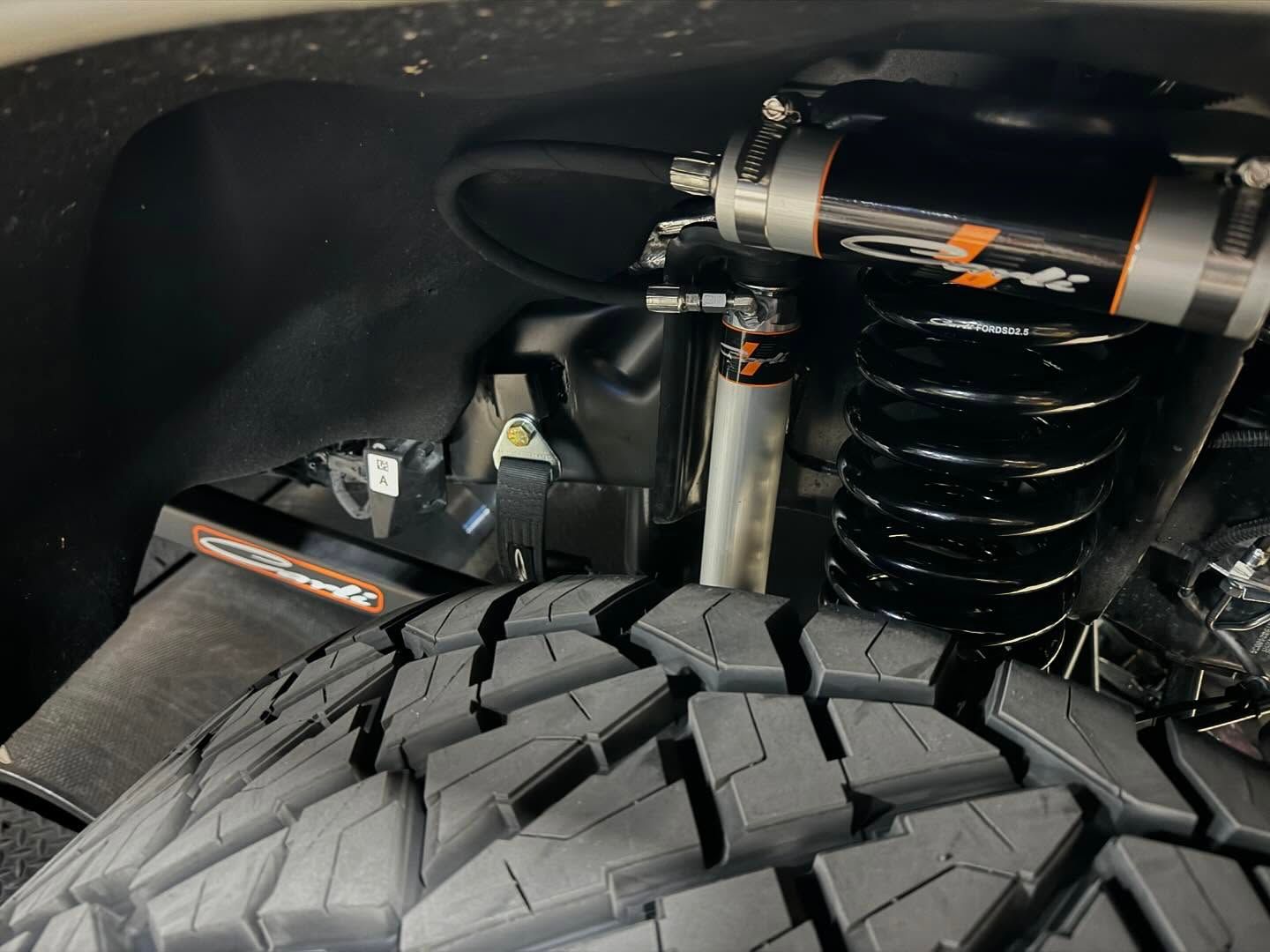Close-up of a truck tire and suspension coil spring under a black wheel well