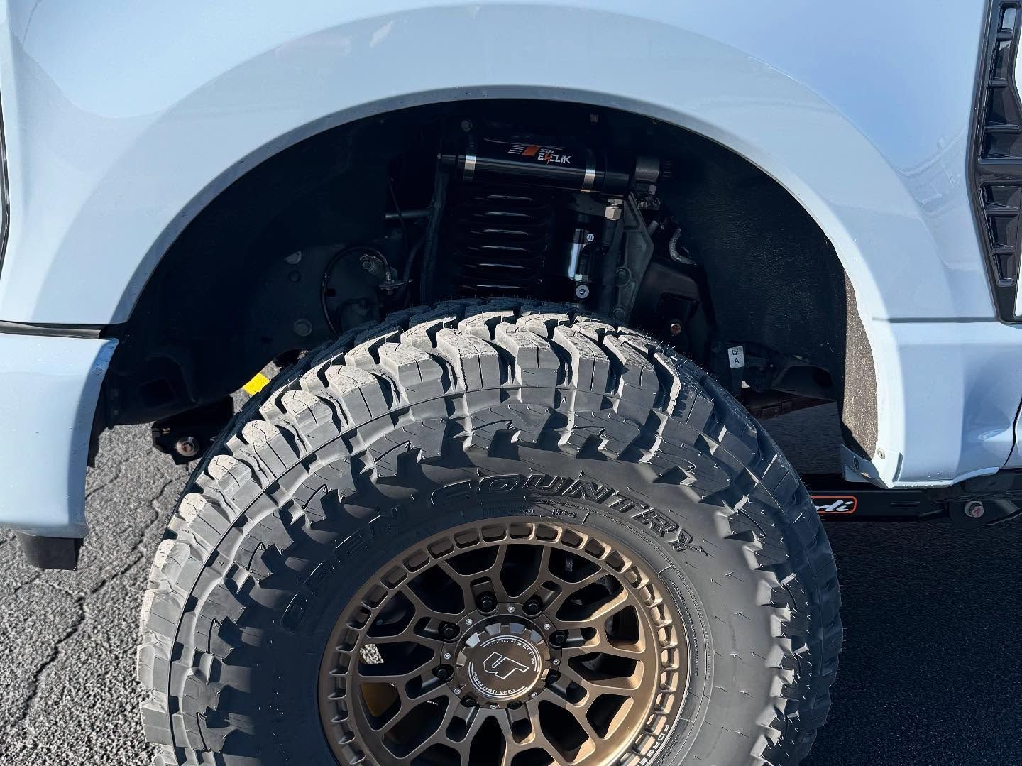 Close-up of a lifted truck’s front wheel and tire under a gray fender.