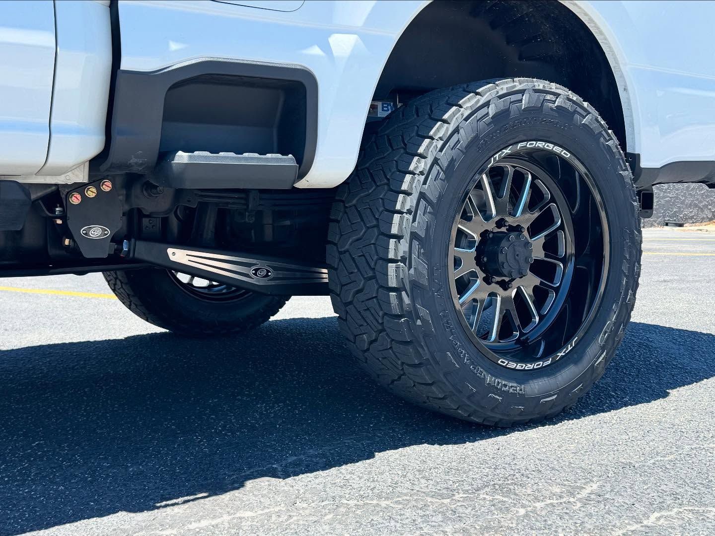 White pickup truck with black off-road wheel and tire parked on pavement