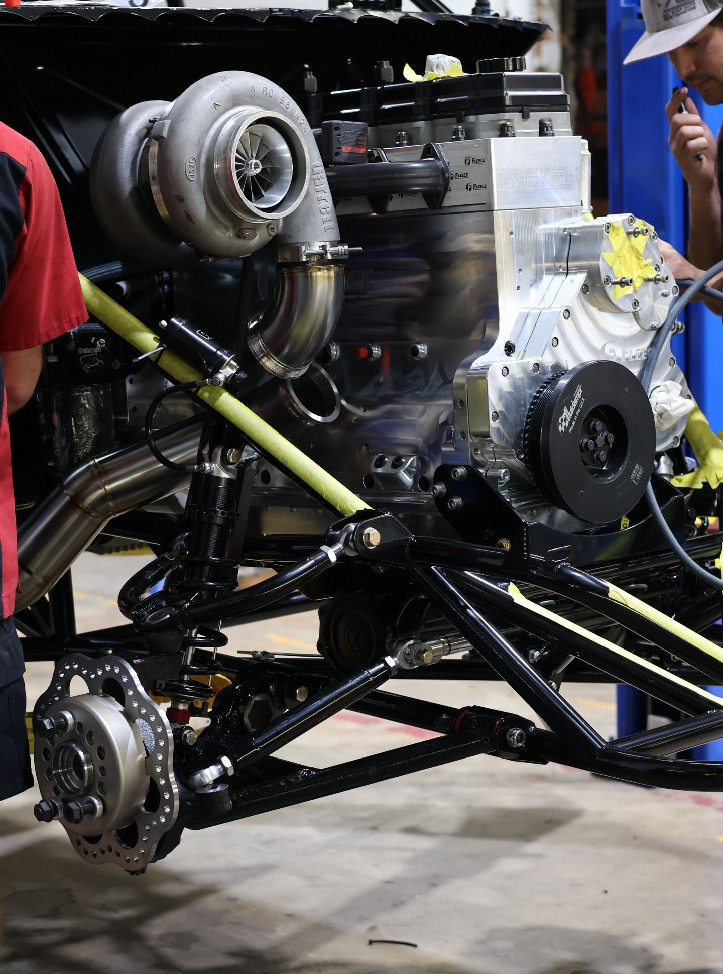 Close-up of a vehicle chassis with a turbo engine and suspension components in a workshop