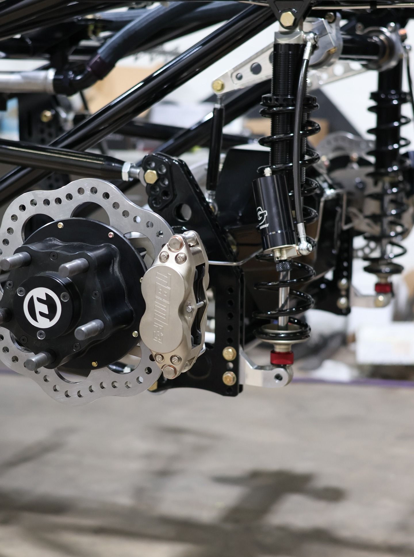 Close-up of a black off-road vehicle suspension and disc brake assembly with metal frame components