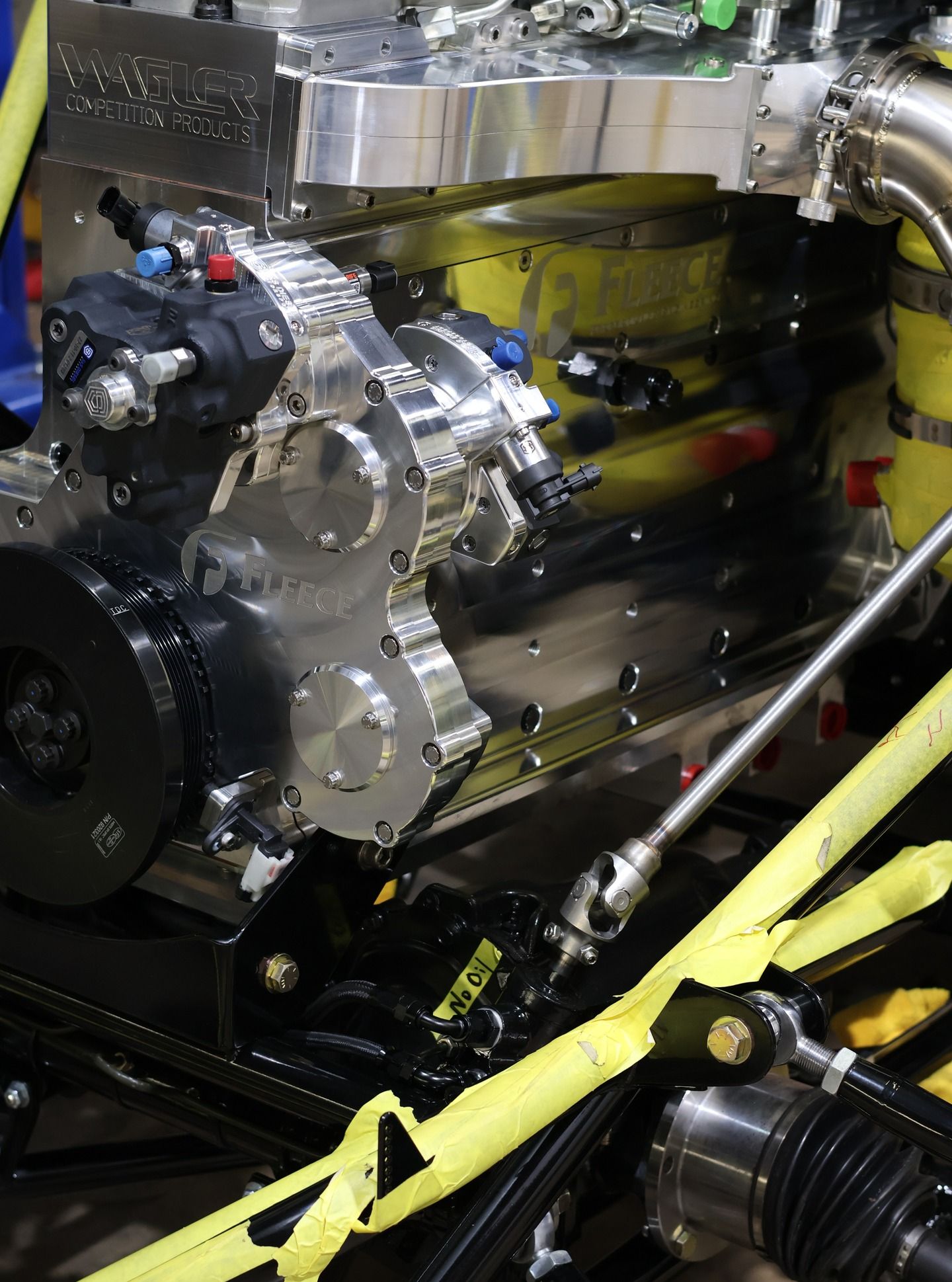 Close-up of a shiny engine with hoses and yellow safety straps in a mechanical bay